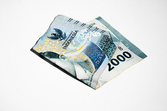 Crumpled rupiah banknotes on a white background.