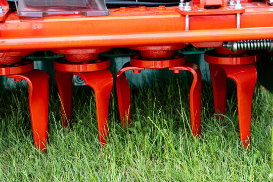 Power harrow rotor assembly with vertical metal tines mounted under reinforced red agricultural frame