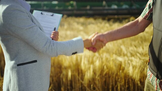 Farmer completing a successful deal with an agricultural consultant in a rural wheat field, with harvest machinery in the background representing productivity and growth.