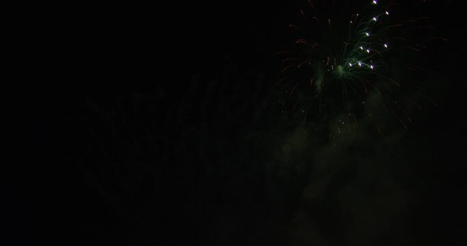 Large, Colorful, Aerial Fireworks Exploding In Smokey Night Sky