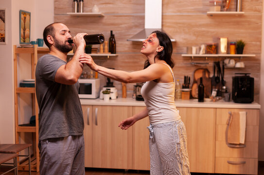 Furious traumatized wife faces a violent husband at home at night after abuse, showing fear, pressure and relationship danger in a domestic crisis.