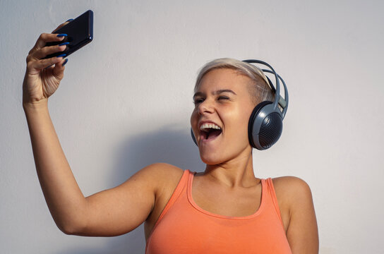 Ecstatic girl listening to music on headphones and taking a selfie