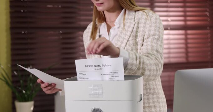 Woman destroying documents with shredder in office, closeup