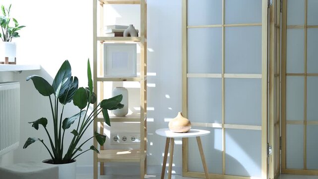 Shelving unit with decor and folding screen indoors, camera moving up. Interior design