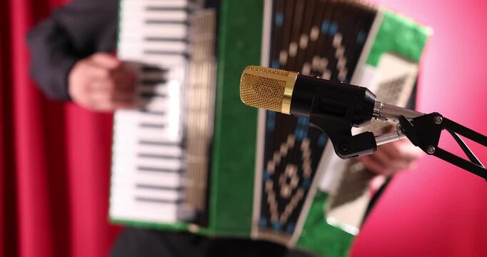 Microphone on stage and man playing piano accordion, selective focus