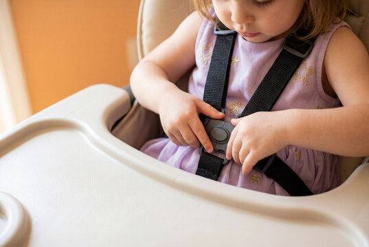 Young child in purple dress unfastening safety belt
