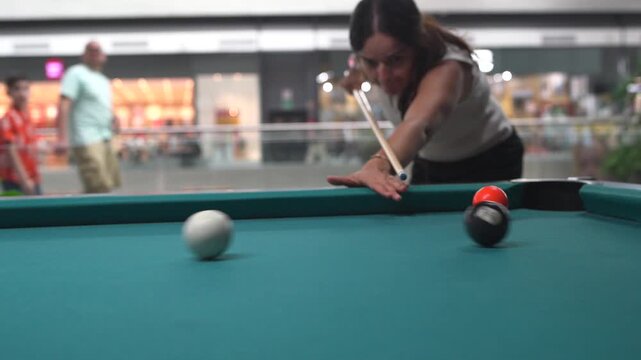Focused woman playing billiards hitting the eight ball