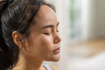 Peaceful asian woman practicing meditation with closed eyes, showing calm serene face profile portrait in bright indoor room, focusing on breathing, wellness, mindfulness, and relaxation © 220 Selfmade studio