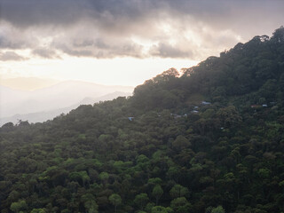 Naklejka premium Clouds gather over a green mountain landscape near a small village