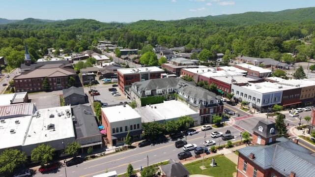Aerial perspective of Brevard, North Carolina, highlighting bustling downtown streets, lush green mountains, and charming historic architecture