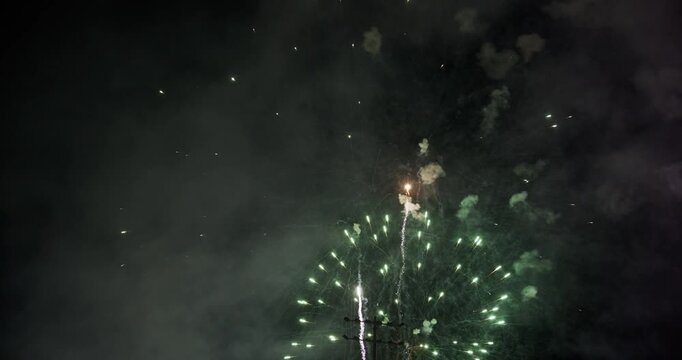 Green Firework Burst Framed by Utility Pole Foreground In Smokey Night Sky