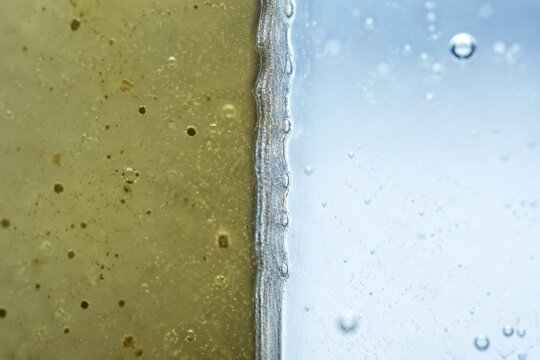 permeable. Extreme close-up of a semi-permeable membrane separating murky liquid from clear liquid. STEM education sheets.