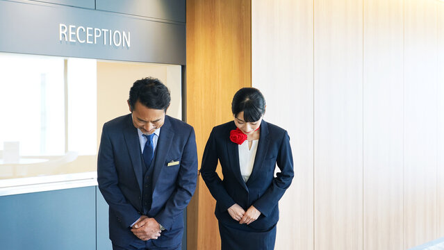 お辞儀するホテルフロントスタッフ