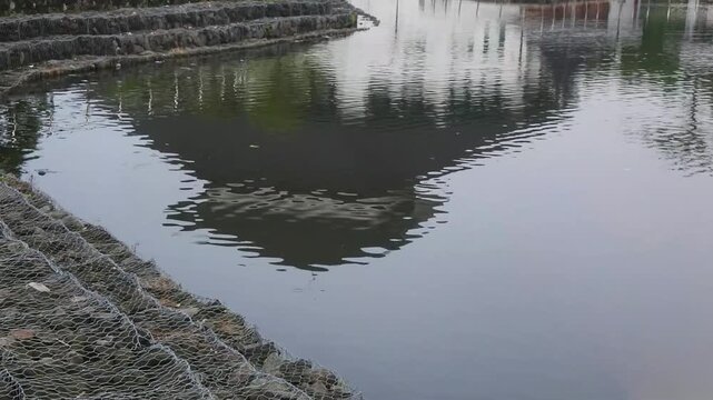 The multi tiered gabion retaining wall with wire cage filled with rocks in a mini dam