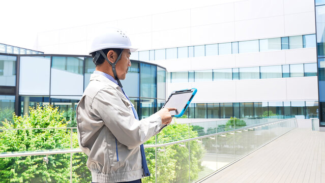 タブレットを見ながら建物をチェックするエンジニア