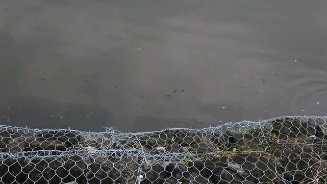 The multi tiered gabion retaining wall with wire cage filled with rocks in a mini dam