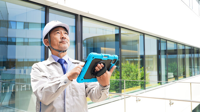 タブレットを使ってビルを点検するエンジニア