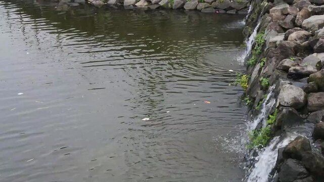 A mini waterfall flowing between rocky embankments in a small dam