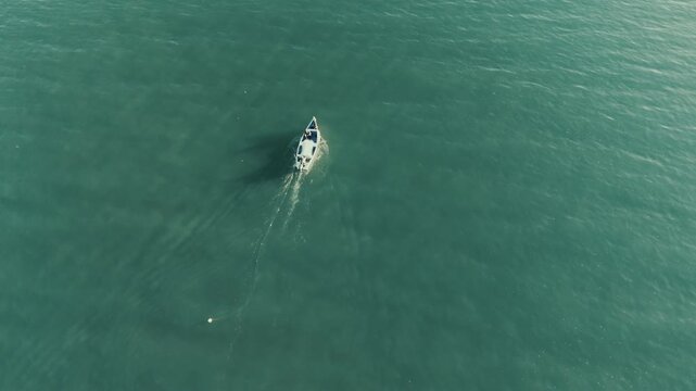 Zenithal drone shot: fisherman with a net on turquoise water in Florian&oacute;polis
