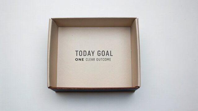 Open cardboard box with motivational message about goals and outcomes on interior surface for personal development or organization