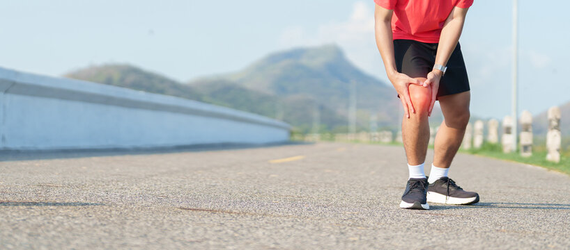 Young adult male runner with knee pain from ACL injury or patellofemoral syndrome. Man having joint ache, ligament tear or patellar tendinitis during running. Sports medical and healthcare concept