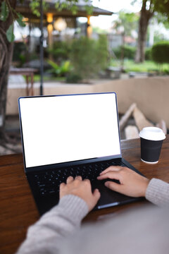 Vertical mockup image of a woman working and typing on laptop computer with blank white desktop screen in cafe