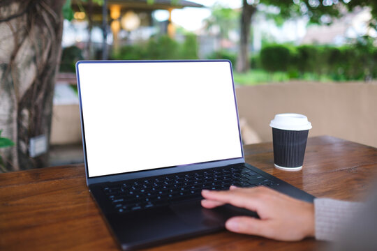 Mockup image of a woman working and touching on laptop computer touchpad with blank white desktop screen in cafe