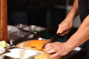 Chef Hands Slicing Fresh Carrots into Julienne Strips on Wooden Board © blueringmedia