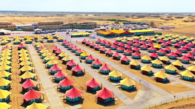 Aerial view of luxury desert camp featuring colorful cone-shaped tents in the Gobi Desert, Qinghai, China.