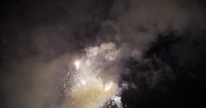 White Firework Burst Scattering Sparks Through Smoky Night Sky