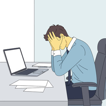 Stressed Businessman In Office Holding His Head By The Desk With Laptop And Papers