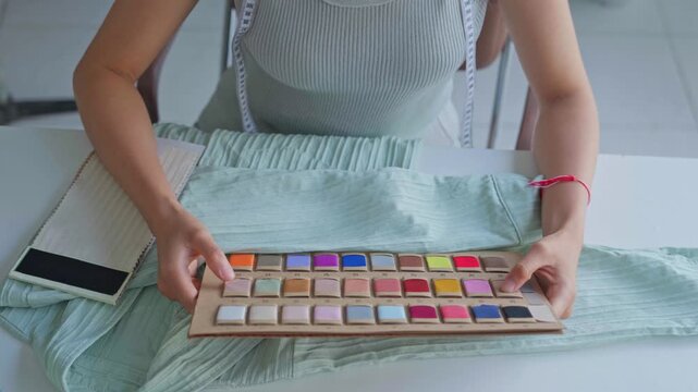 Asian woman tailor holding cloth compare with fabric color chart