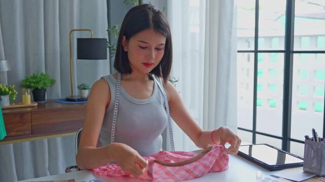 Asian tailor using scissors cut excess threads from cloth