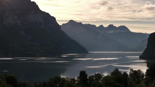 Lake Walen Walensee sunrise sunset bright light behind Swiss Alps mountain range, aerial landscape
