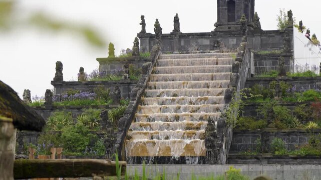 Grand cascading staircase fountain flowing through ornate stone garden at Pairi Daiza Belgium, lush tropical monument