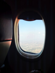 Fototapeta premium View of blue sky and clouds through an airplane window during a flight.