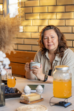 Woman in outdoors gazebo slowly eats breakfast alone