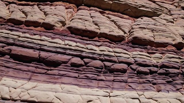Gliding slowly along magnificent striped canyon formation showcasing natural purple and beige rock strata created by thousands years geological sedimentation process in hot dry desert wilderness