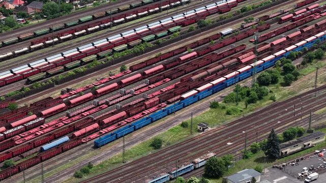 An aerial perspective shows numerous freight wagons arranged on parallel tracks at a busy industrial railway terminal in Hungary.