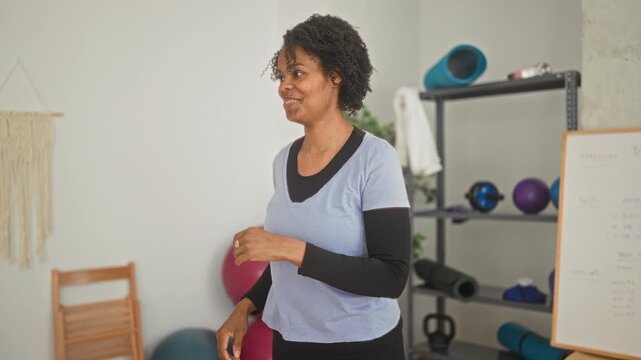 Young woman shadowboxing with clenched fist near exercise mat in a fitness studio; determination focus.