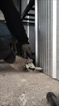 Close up of a worker using a hand rivet gun on the lower frame of a metal structure
