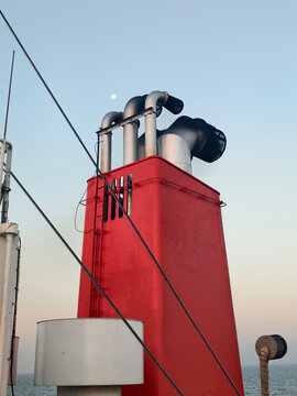 Red funnel and exhaust pipes of a ship cruise ferry liner with blue sky background.