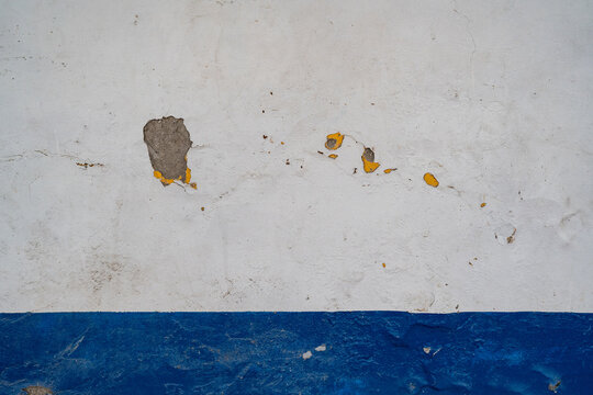 Pared de concreto blanco y azul con pintura descascarada y textura envejecida