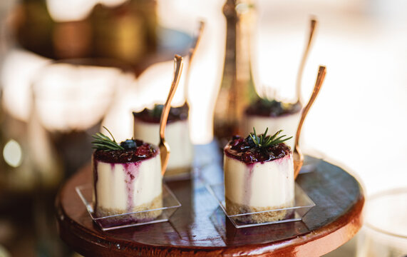 Mini cheesecake con coulis de frutos rojos presentado en elegante mesa de postres para eventos