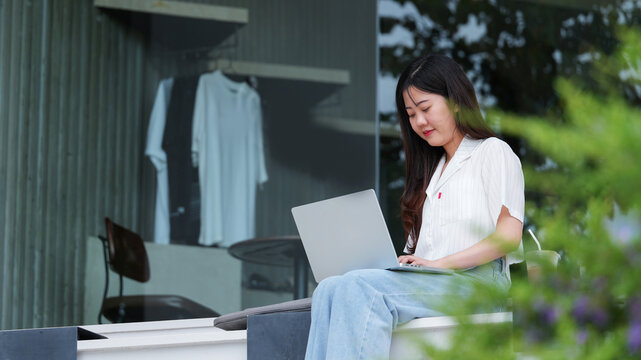 Young businesswoman working on laptop outdoors at a modern cafe