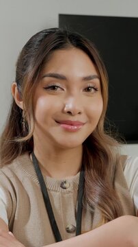 Confident young Asian woman is standing in her office room and posing to the camera.