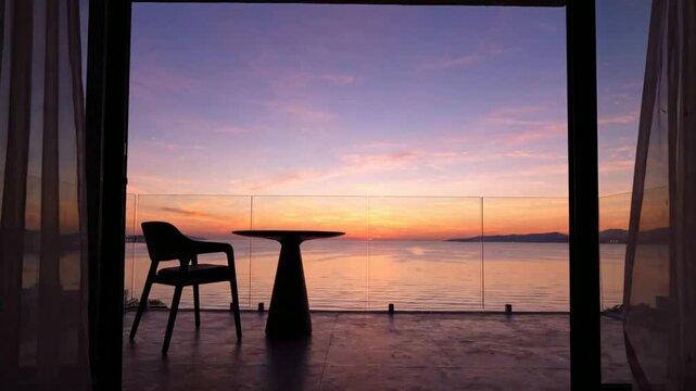 Luxury ocean view balcony at sunset with silhouette table and chair, peaceful vacation resort terrace overlooking tropical sea at twilight