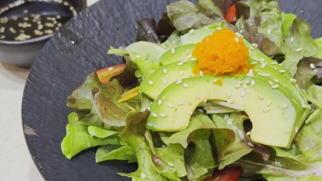 Close-up video of a fresh Japanese-style avocado salad beautifully arranged with mixed vegetables and traditional Japanese dressing. Healthy and colorful salad presentation showcasing authentic Japane