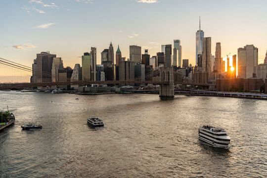 Drone aerial view of lower Manhattan and Brooklyn from the East River Bridge. Panoramic view during golden hour seeing the sunset flare behind the skyscrapers of Tribeca