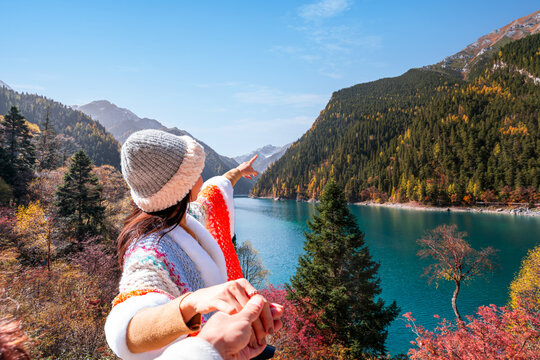 Happy young Asian couple tourist enjoying beautiful colorful autumn leaves and nature scenic view of Long Lake in Jiuzhaigou national park